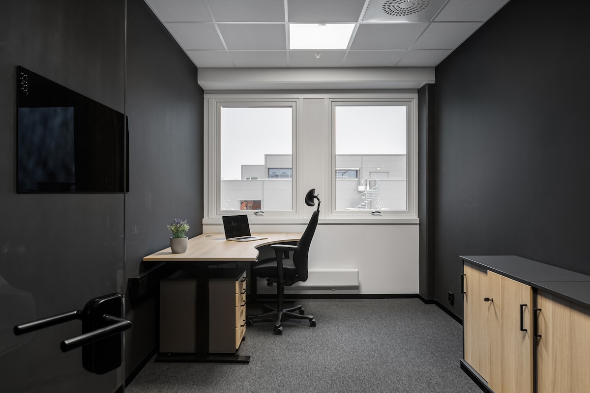 A tidy home office with a desk and an ergonomic task chair by the window