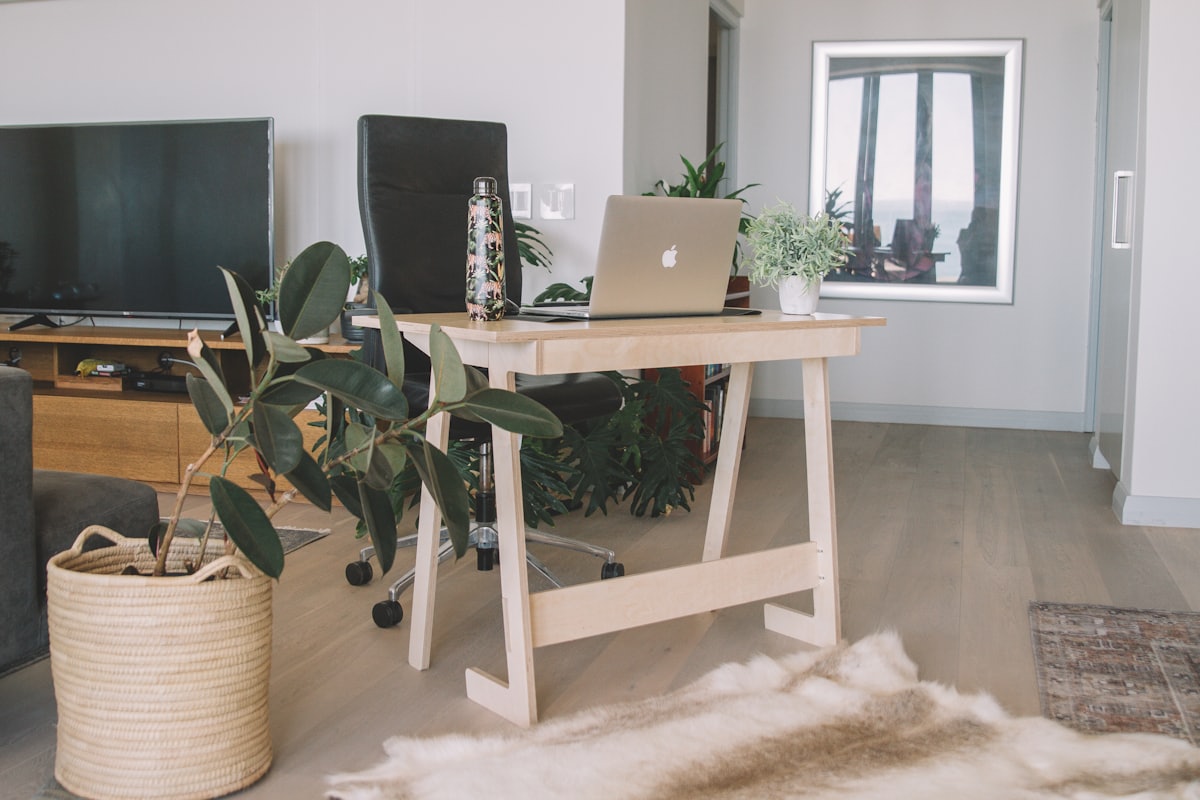 A compact wooden desk with a laptop in a bright small-space apartment